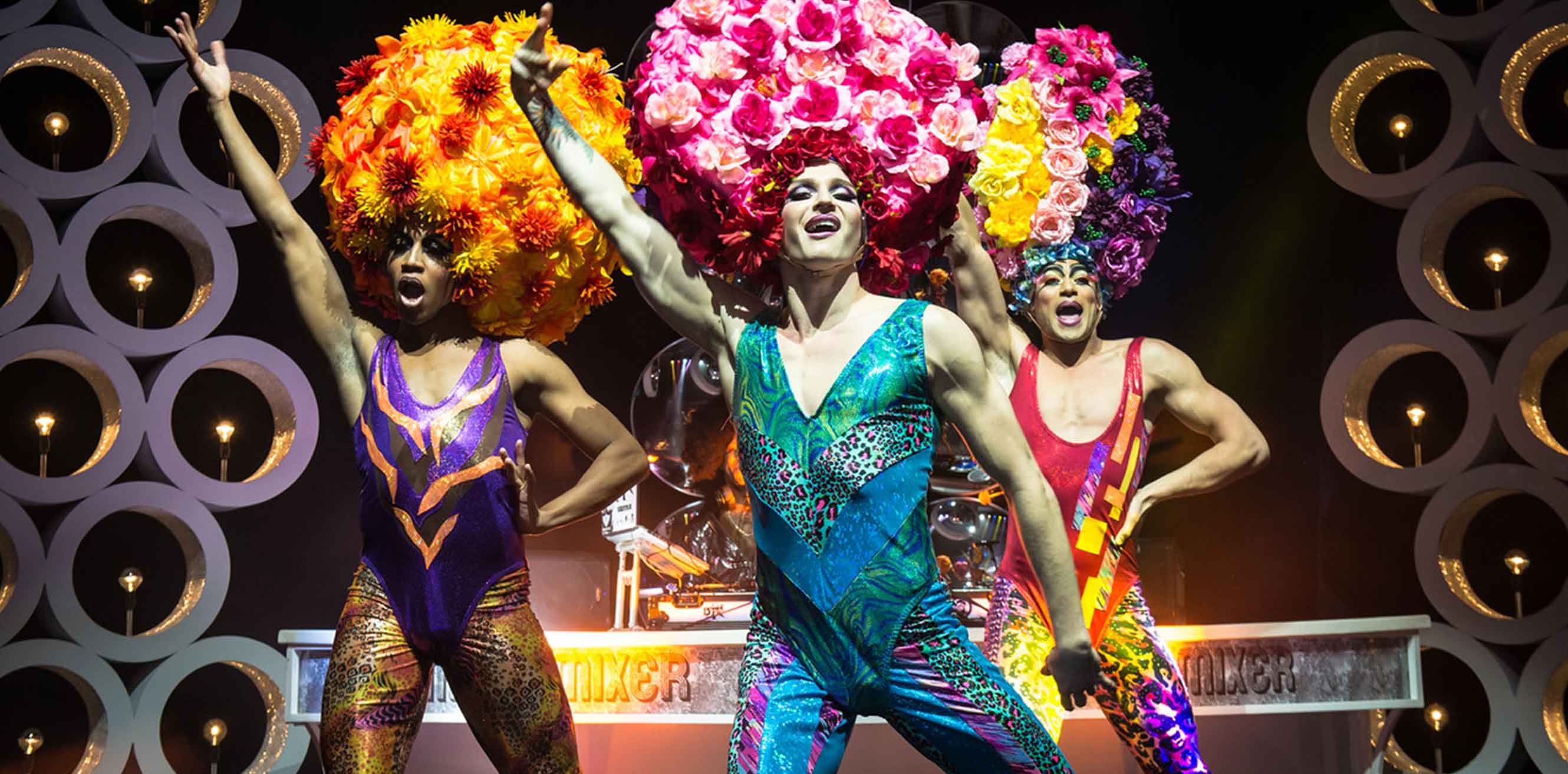 Drag performers wearing floral arrangement wigs